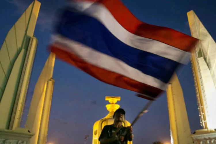 
	Homem com bandeira da Tail&acirc;ndia durante um protesto: governo rejeitou&nbsp;adiamento que pedia a Comiss&atilde;o Eleitoral diante do risco de um aumento da viol&ecirc;ncia
 (Paula Bronstein/Getty Images)