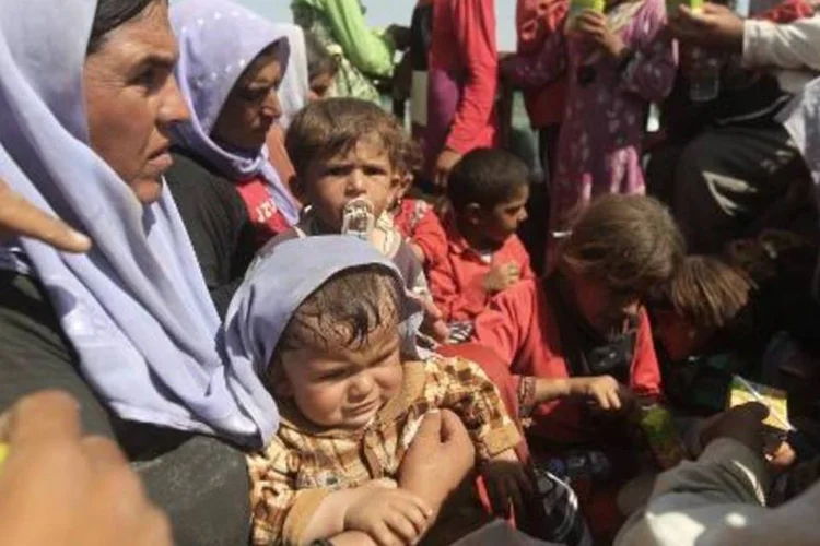 Membros da comunidade Yazidi, que tiveram que deixar suas casas devido à perseguição dos jihadistas, descansam após atravessar a fronteira do Iraque com a Síria (Ahmad al-Rubaye/AFP)