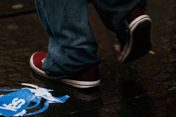 Transeunte passa por um papel da campanha pelo "Sim" após referendo sobre a independência da Escócia  (REUTERS/Russell Cheyne)