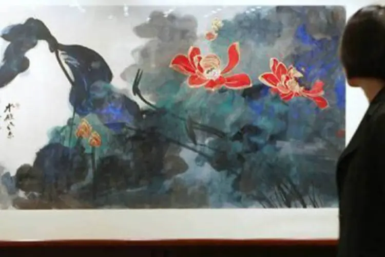 Mulher observa o quadro "The Fragrance of Lotus after Rain" de Zhang Daqian
 (Samantha Sin/AFP)