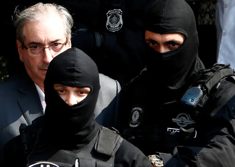 Eduardo Cunha é escoltado por policias federais usando balaclava: um jeito para não chamar a atenção (Rodolfo Buhrer/Reuters)