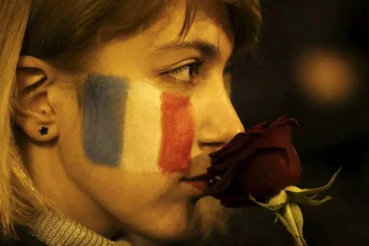 Mulher com bandeira a França pintada no rosto, segura uma flor durante tributo às vítimas em Tsiblisi, Georgia. (REUTERS/David Mdzinarishvili)