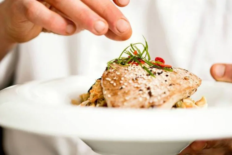 Cozinheiro com prato: cozinheiros amadores podem cobrar, em média, de 40 a 50 dólares por pessoa (Stockyimages/Thinkstock)