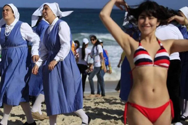 Banhista faz pose enquanto freiras olham para o alto em Copacabana durante visita do Papa ao Rio (Ricardo Moraes/Reuters)