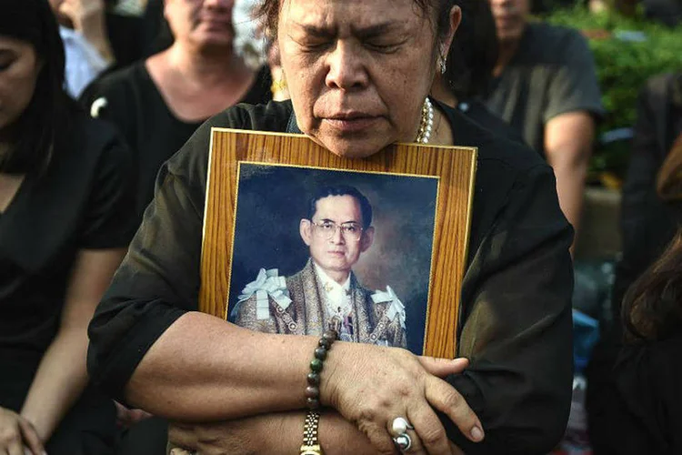 Em Bangkok, uma mulher segura uma foto do rei Bhumibol Adulyadej, morto aos 88 anos 