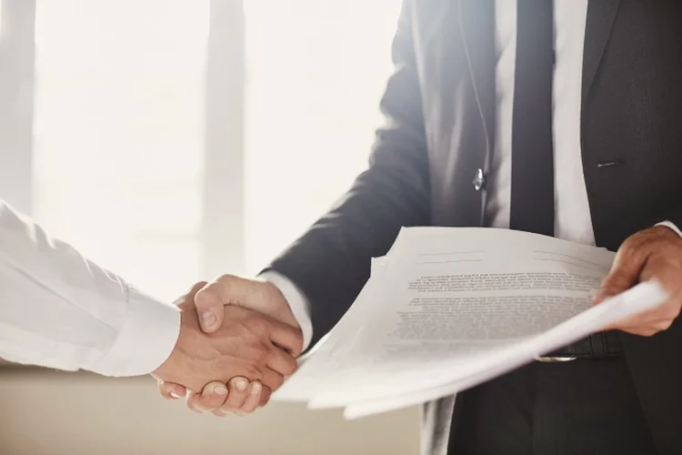 Businessman with documents congratulating his partner (shironosov/Thinkstock)