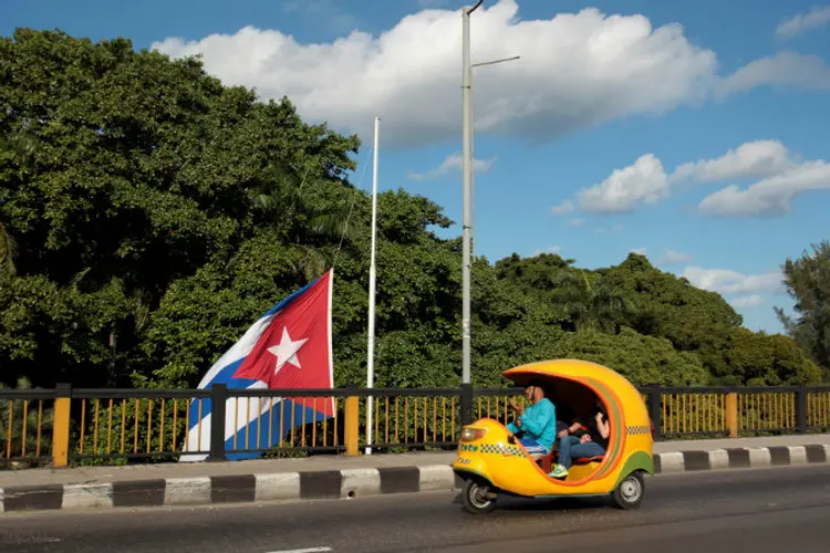 Táxi passa em frente a uma bandeira a meio mastro, em homenagem à morte do líder; (Stringer/Reuters)