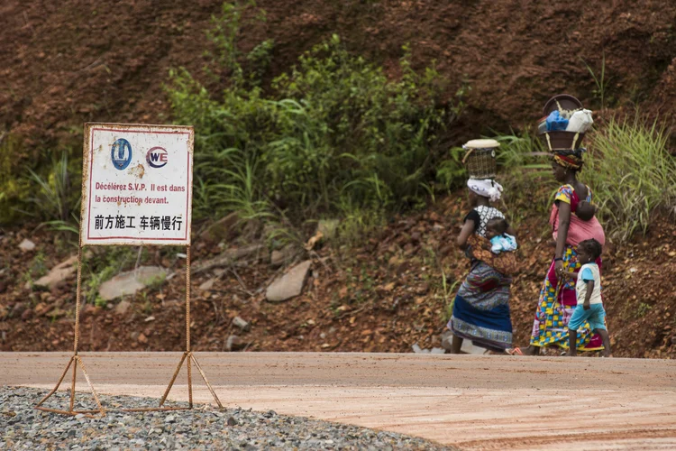 Moradores caminham perto de usina operada pela China na Guiné (Waldo Swiegers/Bloomberg)