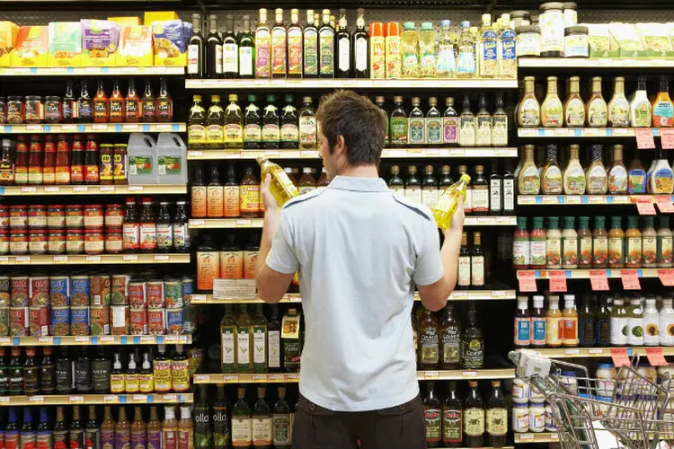 Homem compara preços de produtos em supermercado (Noel Hendrickson/Thinkstock)