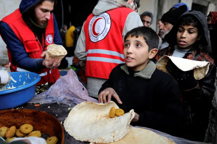 Criança síria refugiada recebe comida de voluntários: "As guerras, atos de terrorismo e deslocamentos forçados que minam a cooperação não são inevitáveis" (Omar Sanadiki/Reuters)
