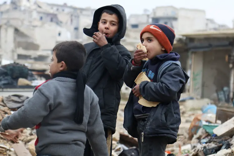 Meninos comem pão enquanto esperam para evacuar Aleppo: negociações ainda estão em andamento (Abdalrhman Ismail/Reuters)