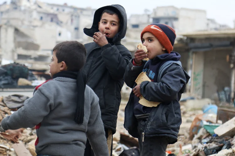 Meninos comem pão enquanto esperam para evacuar Aleppo: negociações ainda estão em andamento (Abdalrhman Ismail/Reuters)