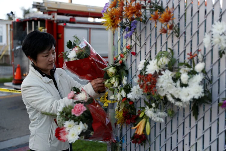 Mulher coloca flores em memorial improvisado no local de incêndio na Califórnia: há dezenas de pessoas desaparecidas em consequência do fogo (Stephen Lam/Reuters)