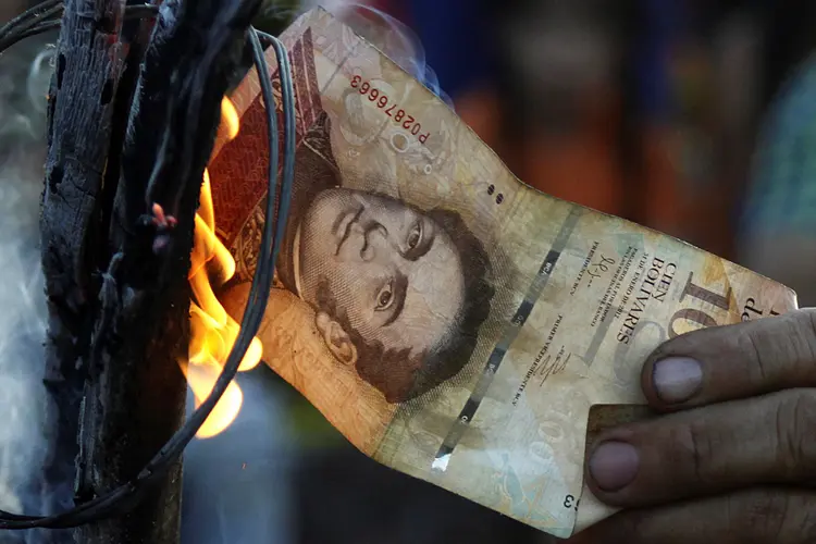Homem queima dinheiro na Venezuela: "não há gasolina, não há notas novas, não há comida" (Carlos Eduardo Ramirez/Reuters)