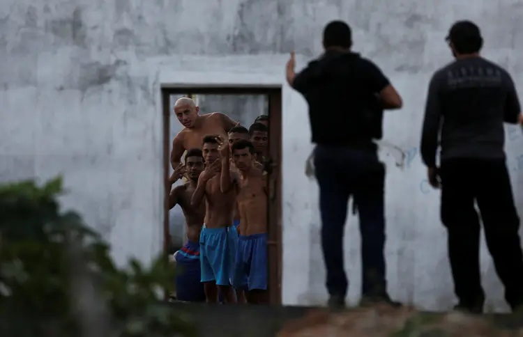 Presos gesticulam para agentes de segurança no presídio de Alcaçuz, em Natal (Nacho Doce/Reuters)