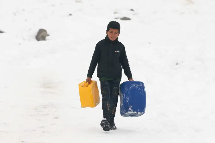 Garoto carrega galões de água em meio à neve em Cabul, Afeganistão (Omar Sobhani/Reuters)