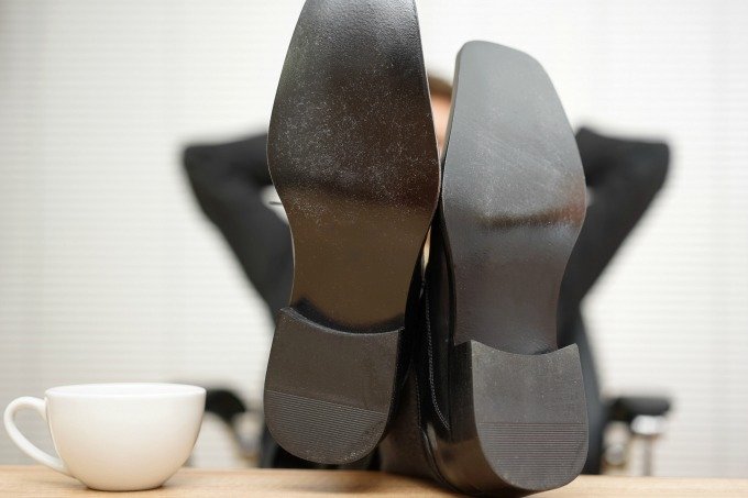 Homem com os pés em cima da mesa de trabalho (BernardaSv/Thinkstock)