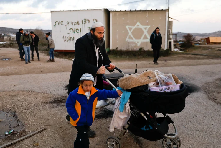 Moradores de ocupação da Cisjordânia carregam seus pertences após remoção feita por Israel (Ronen Zvulun/Reuters)