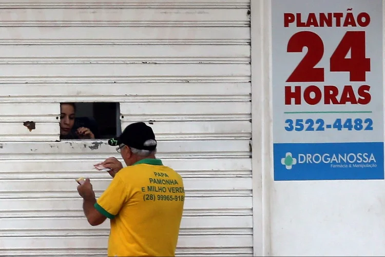 Farmacêutico abre janelinha para atender cliente em Cachoeira do Itapemirim, Espírito Santo, em meio a onda de violência (Paulo Whitaker/Reuters)