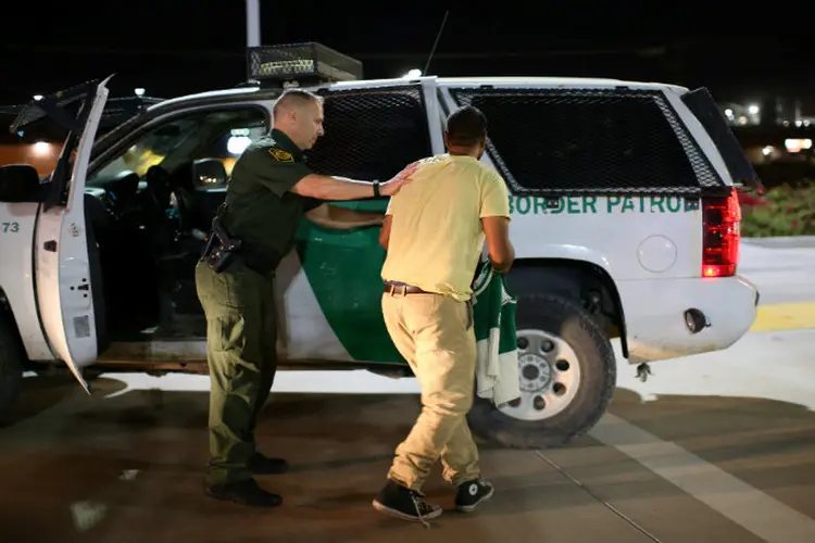 Agente da polícia americana prende um homem indiano após ele ultrapassar a fronteira do México com os Estados Unidos: aumento da repressão começou na segunda (Mike Blake/Reuters)