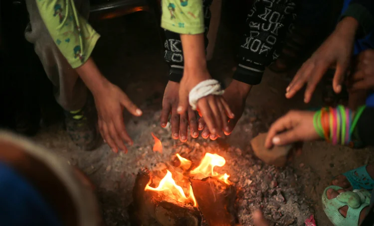 Palestinos se aquecem com fogueira no norte da Faixa de Gaza (Mohammed Salem/Reuters)