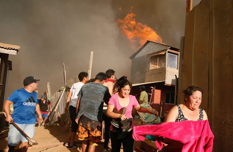 Moradores fogem enquanto carregam seus pertences após incêndio em uma área pobre de Viña del Mar, no Chile, em 12/03/2017 (Rodrigo Garrido/Reuters)