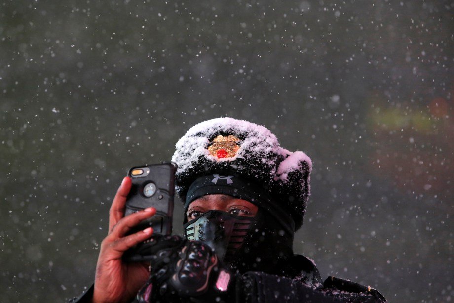 Americano se protege da neve enquanto tira uma foto na Times Square, em Nova York