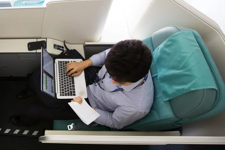 Passageiro usa laptop durante voo (SeongJoon Cho/Bloomberg)