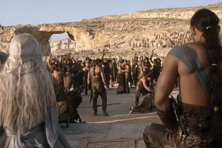 Daenerys e Khal Drogo, de costas, observando o exército Dothraki durante cena da primeira temporada de Game of Thrones. Ao fundo, a Azure Window (HBO/Reprodução)