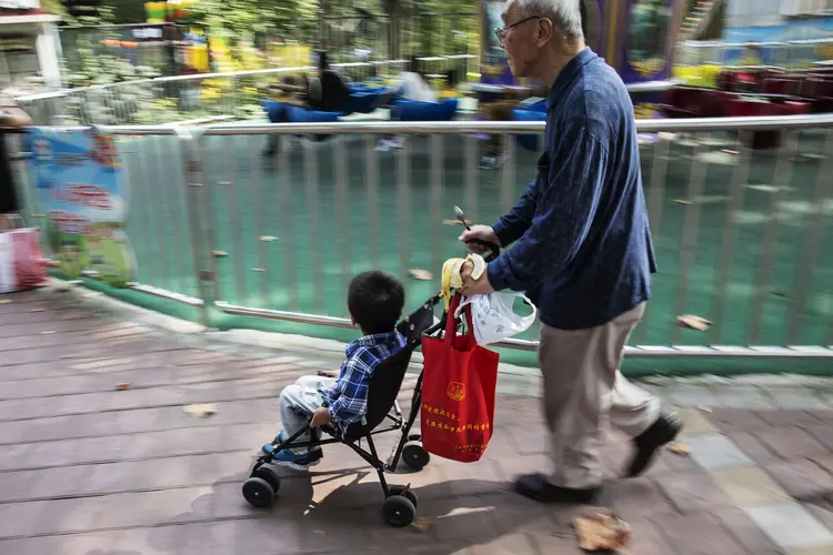 Idoso passeia com criança em carrinho de bebê na China (Qilai Shen/Bloomberg)