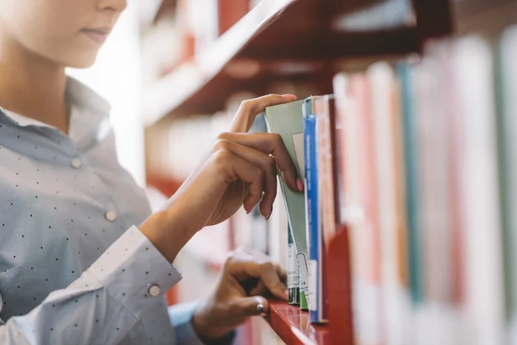 Mulher procurando livro em biblioteca (demaerre/Thinkstock)