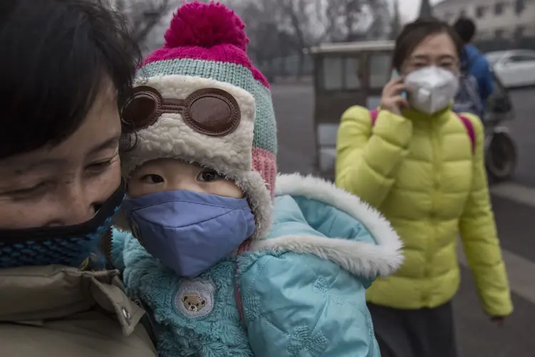 Mãe e bebê usam máscaras de proteção contra a poluição em Pequim, na China (Kevin Frayer/Getty Images)