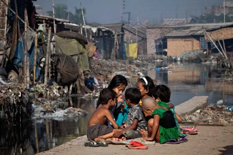 Crianças brincam ao lado de um canal poluído no bairro de Hazaribagh, em Dhaka, Bangladesh. (Stringer/Getty Images)