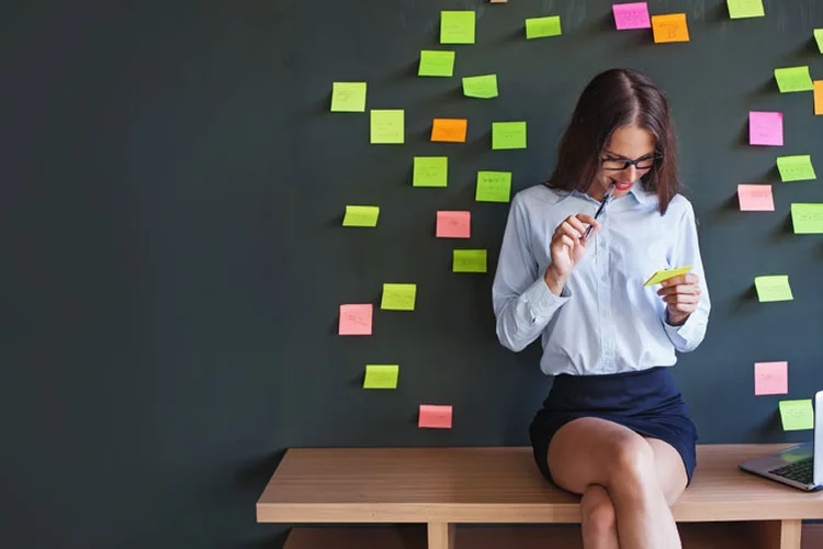 Mulher olhando para um post-it (LiudmylaSupynska/Thinkstock)