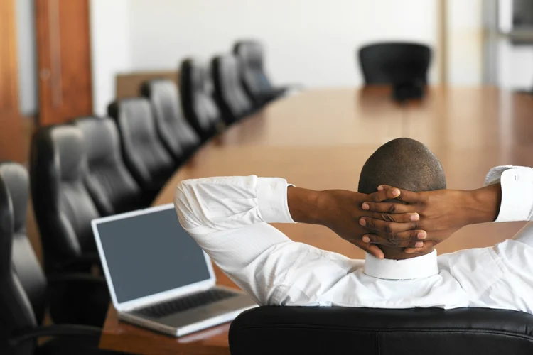 Executivo relaxado em sala de reunião (Stockbyte/Thinkstock)