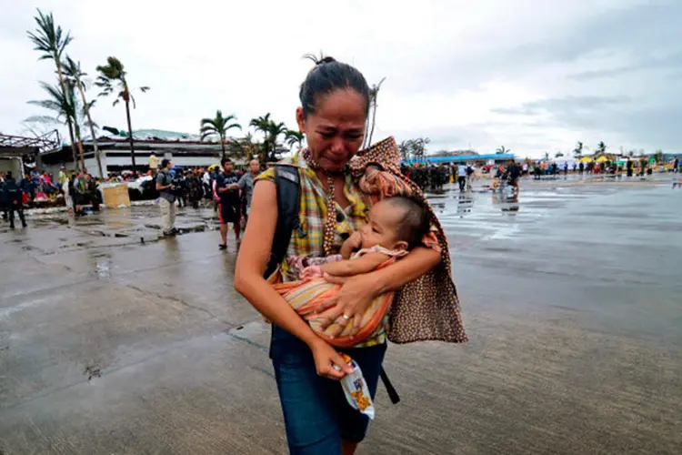 Uma mulher chora enquanto leva uma criança a um avião militar para evacuar a área que foi devastada pelo tufão Haiyan em 12 de novembro de 2013 em Leyte, Filipinas (Dondi Tawatao / Stringer/Getty Images)