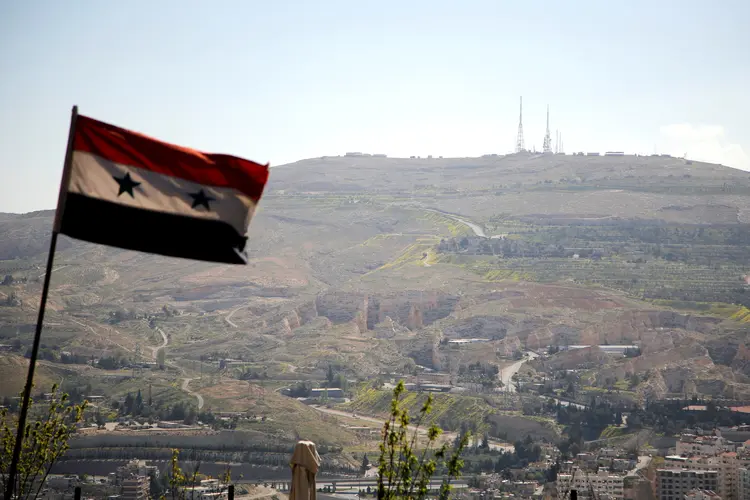 Bandeira da Síria em frente à montanha Qasioun, em Damasco (Omar Sanadiki/Reuters)