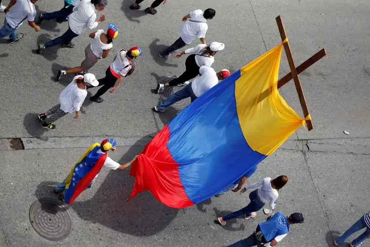 Manifestantes carregam cruz com as cores da Venezuela em protesto contra as mortes ocorridas durante manifestações (Christian Varon/Reuters)