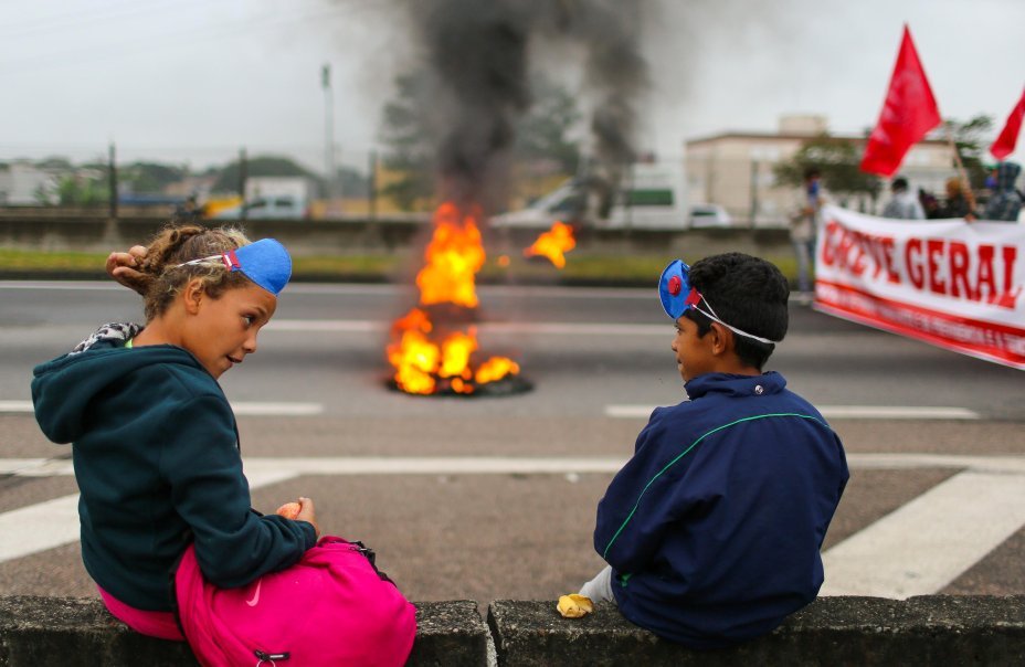 Crianças sentadas perto de barricada na rodovia Dutra, durante greve geral contra reformas do governo Temer