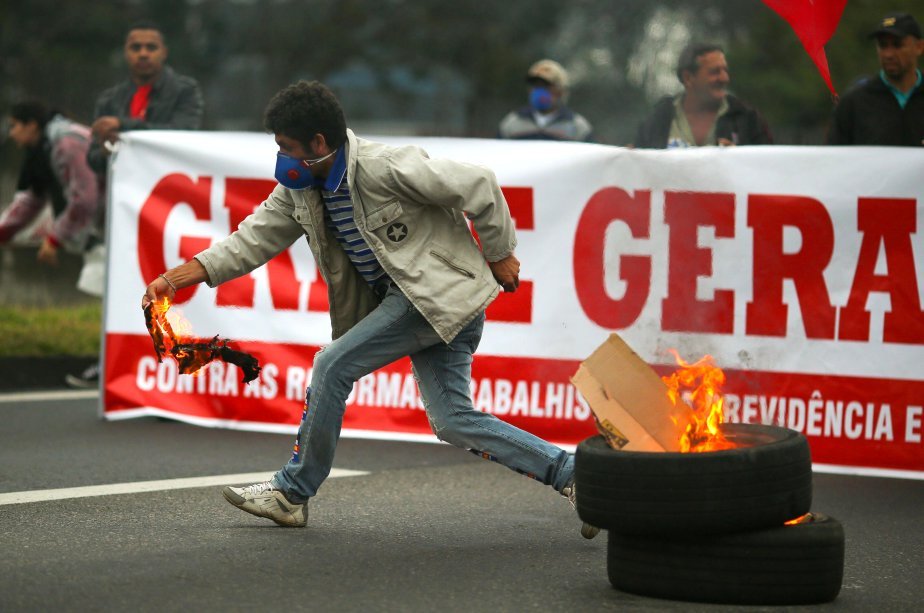 Manifestante prepara barricada na rodovia Dutra, durante greve geral, contra medidas do governo Temer