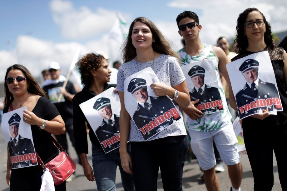 Pessoas seguram uma foto de Temer vestido de Hitler durante protesto no Congresso Nacional em Brasília na greve geral