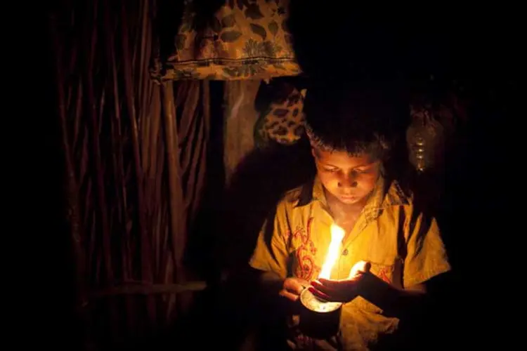 Menino segura uma vela em sua casa, que não tem eletricidade, em Bangladesh.  (Stringer/Getty Images)