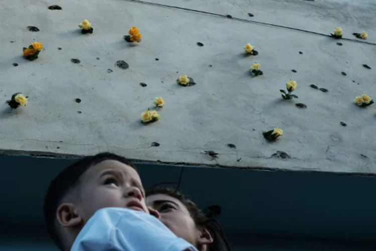 Flores são depositadas em buracos de bala na fachada de uma loja do Complexo da Maré, durante uma manifestação contra a violência em favelas do Rio (YASUYOSHI CHIBA/AFP)