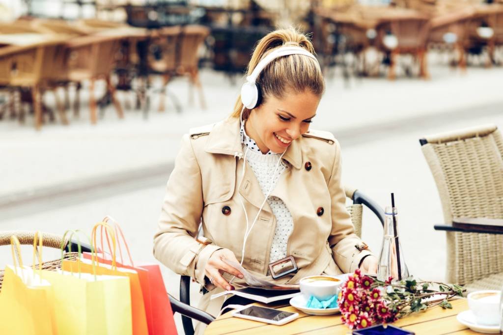 Mulher com fones de ouvido e sacolas de compra: o sound branding é uma estratégia para reforçar sua marca e fidelizar os clientes por meio dos sons (Foto/Thinkstock)