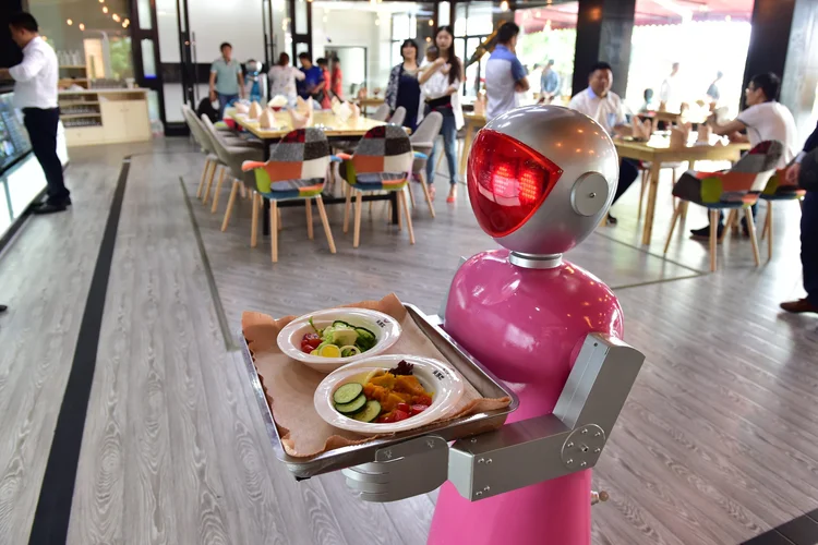 Robô carrega bandejas de comida em restaurante na China (VCG/Getty Images)