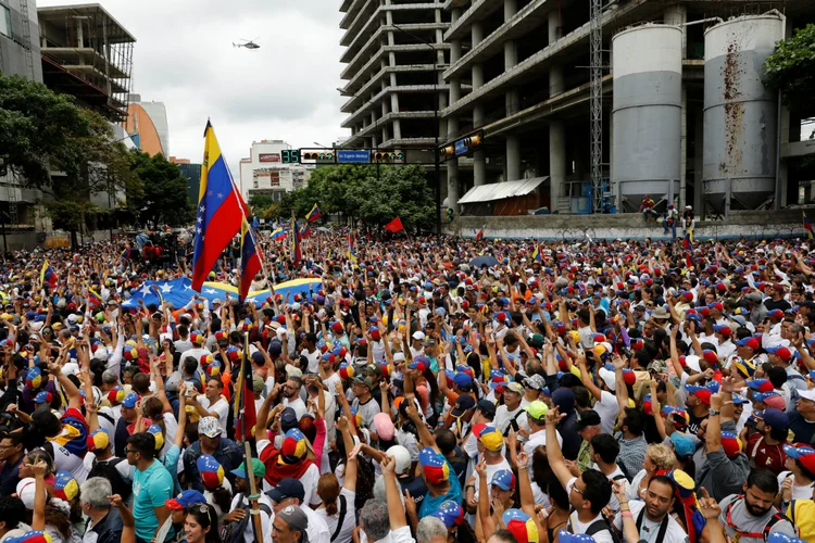 Pessoas protestam enquanto helicóptero passa em manifestação do Dia do Trabalho em Caracas (Venezuela): manifestantes foram dispersados com bombas de gás lacrimogêneo (Carlos Garcia Rawlins/Reuters)