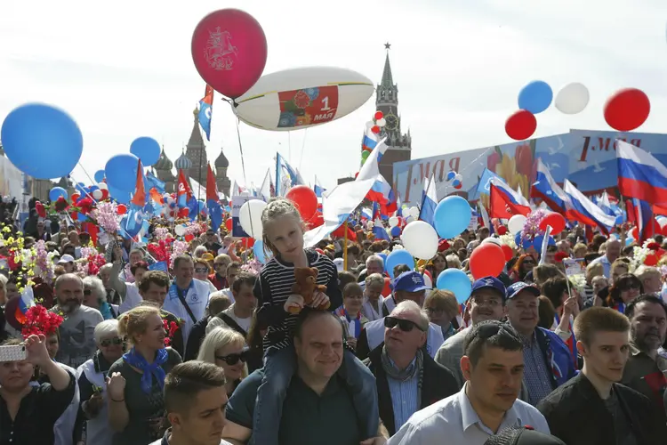 Pessoas participam de manifestação do Dia do Trabalho na Praça Vermelha, em Moscou (Rússia): elas agitando bandeiras e balões junto aos muros do Kremlin (Sergei Karpukhin/Reuters)