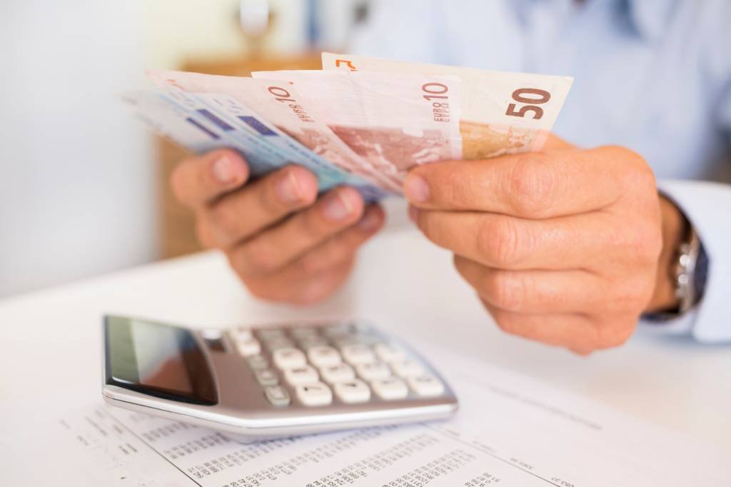 Homem com calculadora e dinheiro (LDProd/Thinkstock)