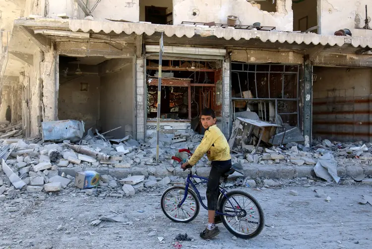 BOMBARDEIOS: Menino anda de bicicleta em meio aos escombros na cidade de Aleppo, na Síria / Abdalrhman Ismail