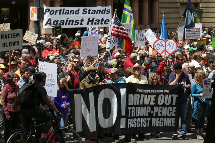 Dezenas de manifestantes anti-Trump mascarados e cobertos de preto agitaram uma bandeira de "Ação Antifascista" contra ativistas pró-Trump que estavam do outro lado da rua (David Ryder/Reuters)